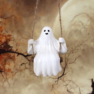 Detail of a white resin ghost figurine sitting on a rope swing for Halloween garden decor