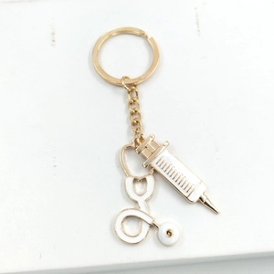 Close-up of golden stethoscope and syringe charms on a medical keychain set