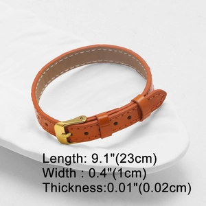 Detail view of adjustable orange leather strap with golden buckle and stitching details