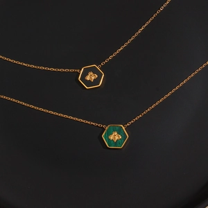 Close-up of gold hexagonal bee pendants with black and green malachite inlays