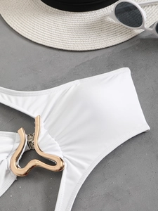 Detail of white swimsuit featuring a golden wave-shaped metal buckle and premium fabric
