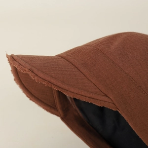 Macro shot of brown newsboy hat showing frayed edge design and cotton linen texture