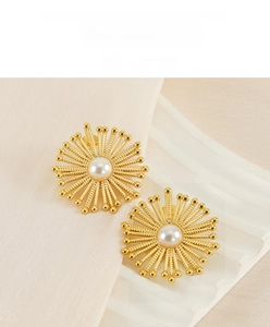 Detail of gold stainless steel flower earrings with pearls and vintage sun design