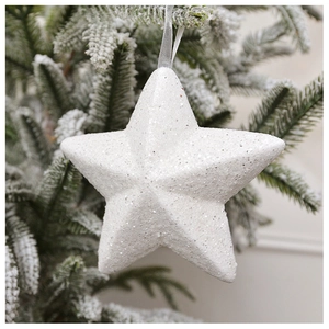 Close-up of white star Christmas ornament with silver glitter on snowy pine branches