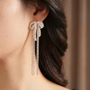 Silver bow tassel earrings with zircon stones worn by a model in a luxury style