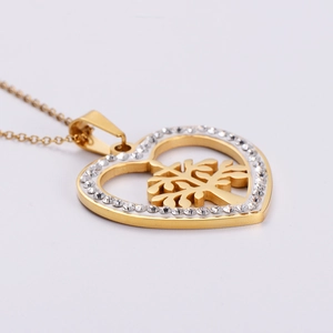 Golden heart necklace with tree of life pendant and white rhinestones on white background
