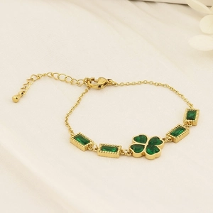 Detail view of gold stainless steel bracelet with clover motif and green stones