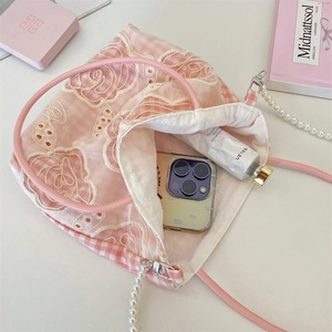 Détail du sac en dentelle rose avec poignée en perles montrant l'espace de rangement