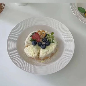 Close-up of a strawberry cake on a white ceramic plate with a minimalist ribbed rim