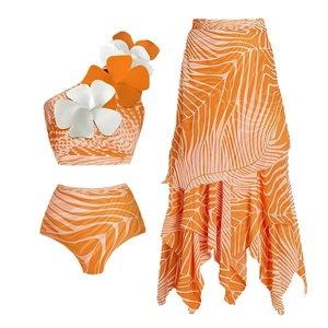 Detail of orange one-shoulder swimsuit with 3D floral accents and ruffle sarong skirt