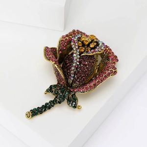 Elegant rose brooch in antique bronze with colorful rhinestones on a white pedestal