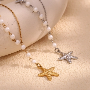 Close-up of asymmetric gold and silver starfish pendants with small pearls on necklaces