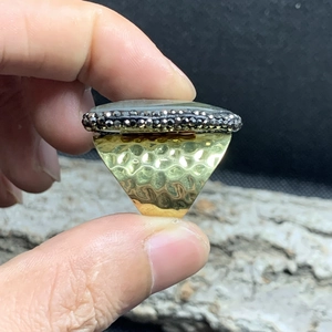Detailed macro of golden wide ring featuring hammered texture and inlaid natural stone
