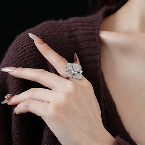 Gros plan d'une bague fleur étincelante avec zircon émeraude sur le doigt