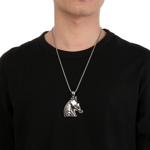 Detail of a vintage silver horse head pendant on a male model wearing a black t-shirt