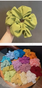 Detail showing oversized chiffon scrunchies in various candy colors on a wooden table
