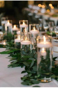 Detailopname van witte drijfkaarsen in glazen vazen met romantisch warm bokeh-licht
