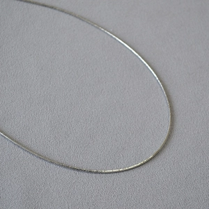 Girocollo minimalista in ottone argento con finitura lucida mostrato in macro primo piano