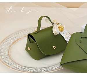 Detail of green faux leather wedding candy box with gold charms and ribbon ties
