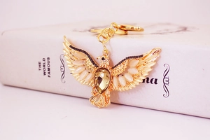 Close-up of a golden eagle keychain featuring an amber crystal and beige gemstones