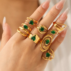 Set of gold stainless steel rings with green zircon crystals on a model hand