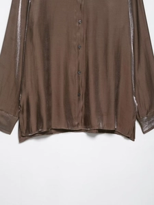 Detail shot of bronze satin shirt showing metallic texture buttons and sleeve cuffs