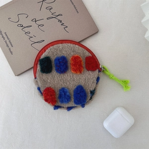 Detail view of khaki plush round pouch with colorful dots and green woven cord puller