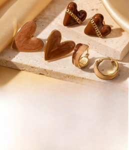 Close-up of heart-shaped earrings and hoops with marble pattern on titanium steel