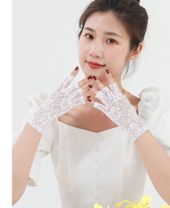 Close-up of white lace fingerless gloves with floral patterns on a model in white dress