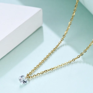 Macro detail of 6mm single diamond pendant on gold chain necklace for women