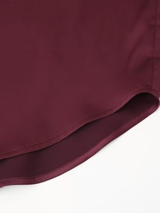 Detalle del dobladillo de camisa de satén burdeos con textura suave y costura de calidad