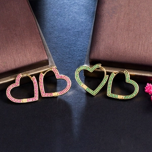 Macro dettagliata di grandi orecchini a cuore placcati in oro con zirconi rosa e verdi