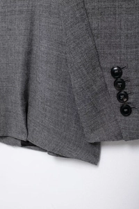 Detail view of gray wool blend blazer cuff with four black buttons and fabric texture