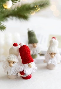 Close-up of four mini Christmas gnomes with knit hats and wooden bases in festive setting