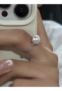 Vista dettagliata di un anello con perla bianca e fascia in argento indossato