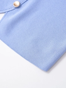 Détail du tricot côtelé bleu clair avec un bouton doré poli et une texture de maille fine