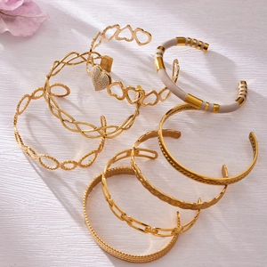 Chic gold-tone bangle set with heart charms and white enamel on a white textured background