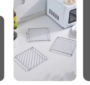 Stack of three square chrome metal trivets on a marble kitchen countertop for hot pans