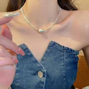 Dettaglio di una collana multistrato argento con perla indossata da una modella