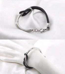 Detail of titanium steel bracelet featuring black leather knots and lobster clasp on wrist