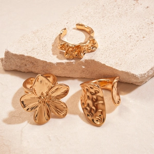 Minimalist gold pleated flower ring with irregular hammered texture on stone background