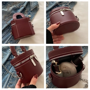 Détails du sac seau bordeaux cylindrique avec coutures blanches et chaînes argentées