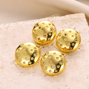 Detailed view of four golden star-set zircon earrings on a textured stone surface