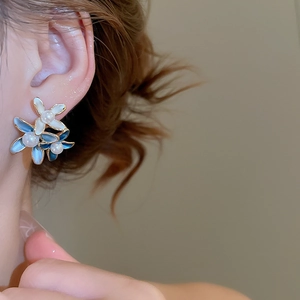 Detail view of 18K gold plated flower earring with pearls on a model's ear