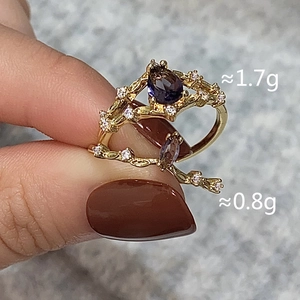 Detail of two-piece gold rings with pear-shaped purple zircon and vine texture