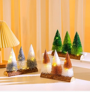 Miniature bottle brush Christmas trees with LED lights on a wooden base for table decoration