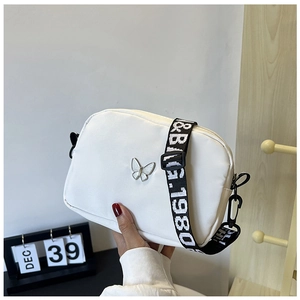 White square crossbody bag with silver butterfly ornament and stylish nylon strap detail