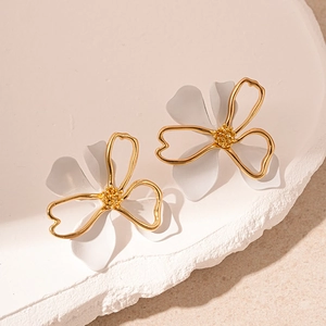 Detail of elegant gold-rimmed white double-layer petal earrings on a stone base