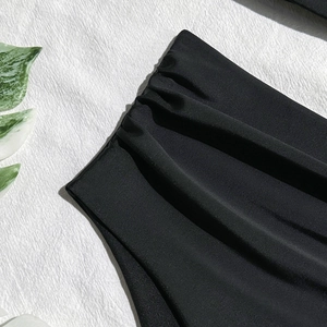 Close-up of ruched black high-stretch swimsuit fabric with detailed textured pleats