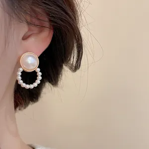 Detailed view of elegant square pearl drop earrings with gold plating on a female model